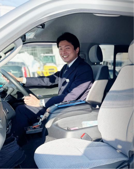 笑顔でハンドルを握る運転席のビジネスマン。